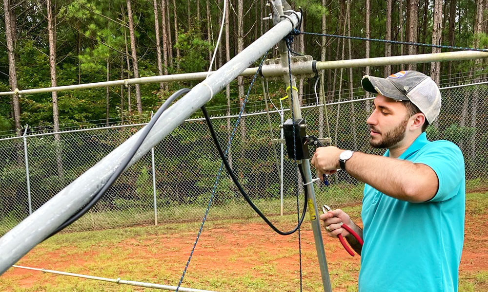 Man working outside adjusting a radio antenna.