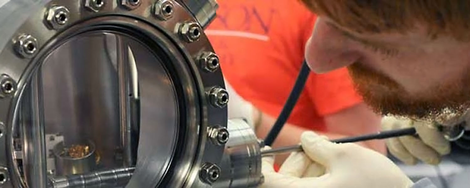 Man looking into research device in lab.