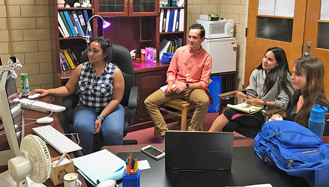 Students in room sitting and looking at computer display.