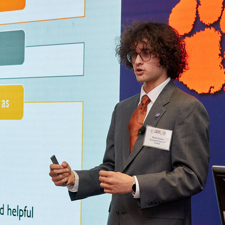 Man in front of a display wall speaking.