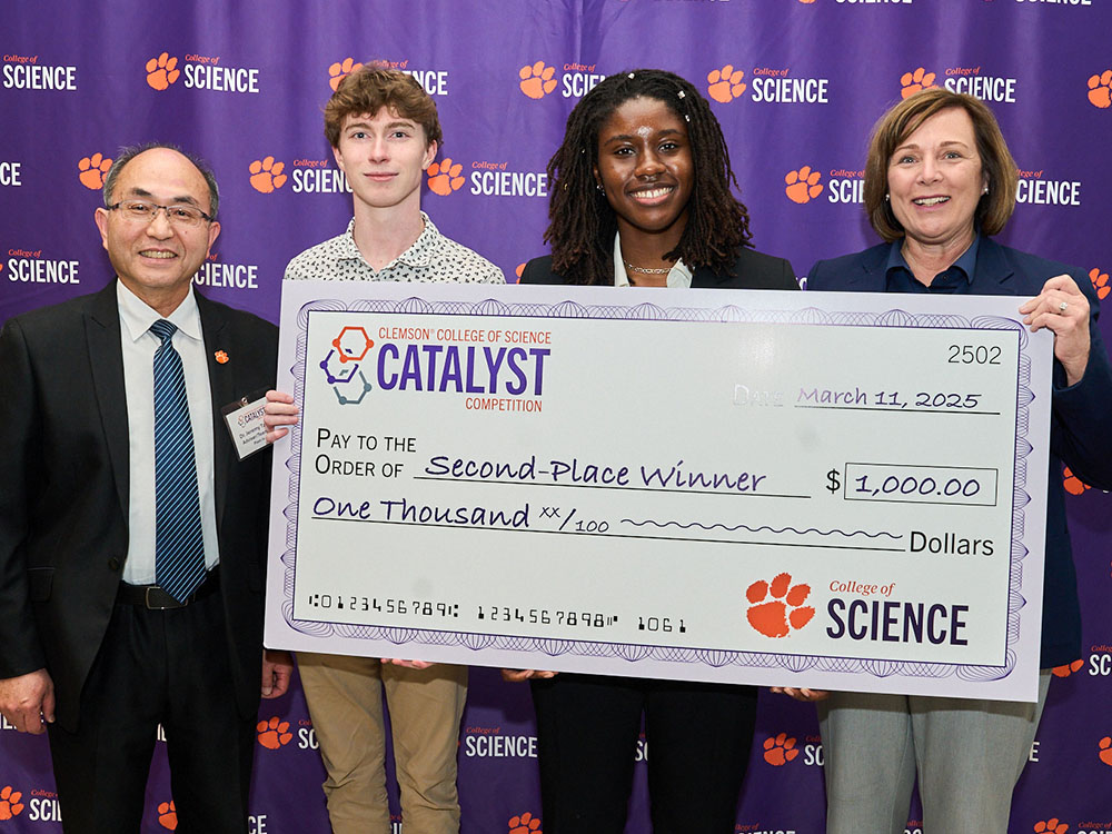 Four people in front of a College of Science purple step-and-repeat wall, holding Catalyst first-place-winner check for $2,500.