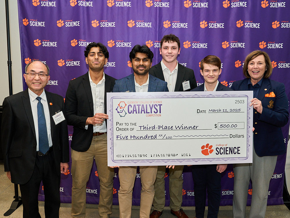 Six people in front of a College of Science purple step-and-repeat wall, holding Catalyst first-place-winner check for $2,500.