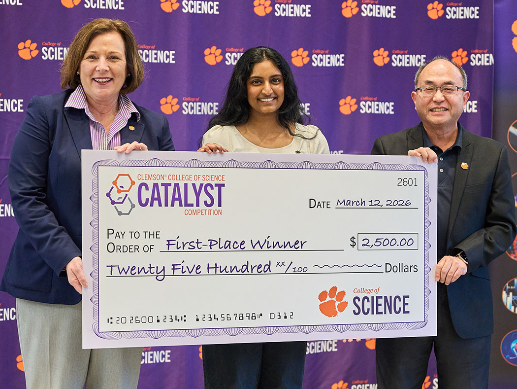 Three people in front of a College of Science purple step-and-repeat wall, holding Catalyst first-place-winner check for $2,500.