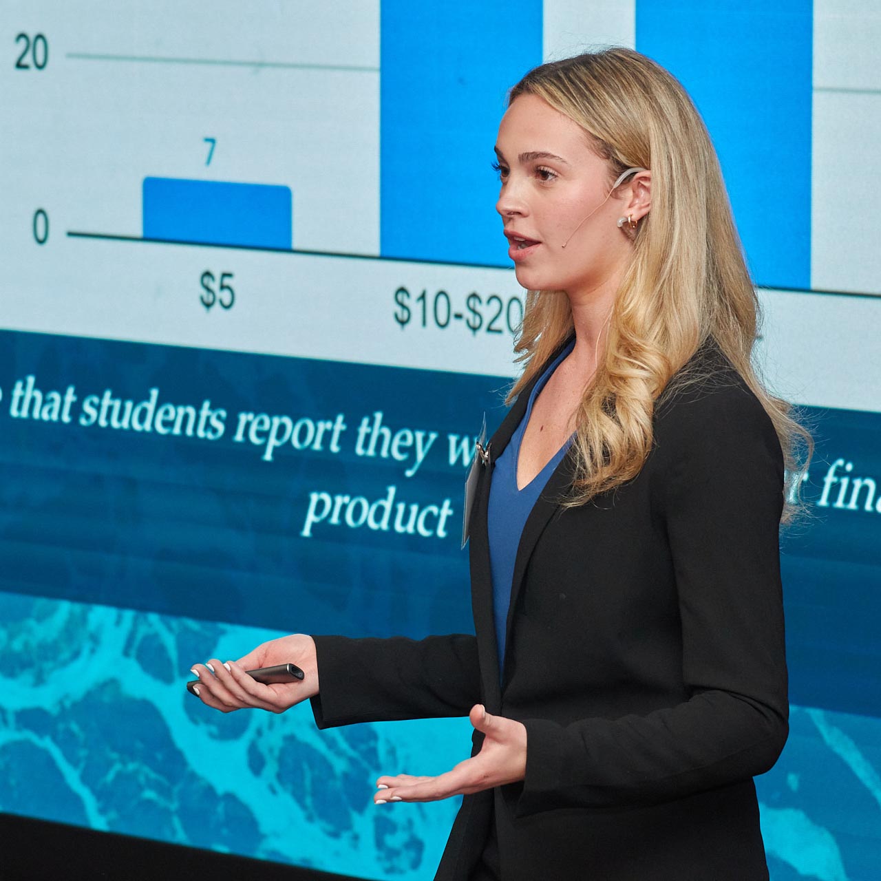 Girl giving presentation with video board behind her.