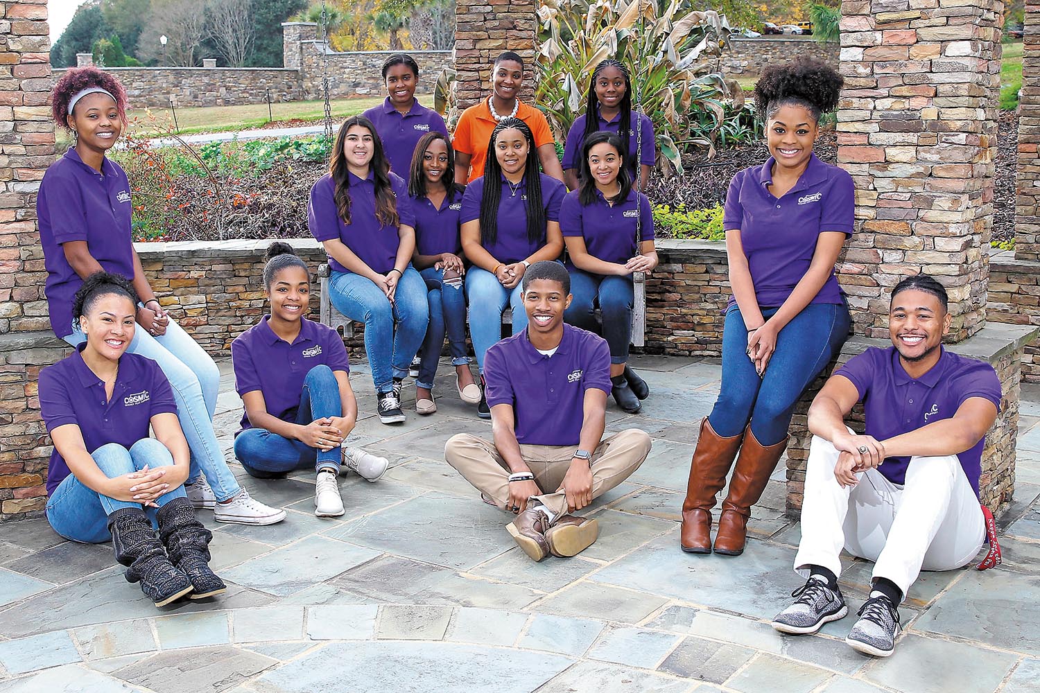 Group of students standing and sitting in a brick courtyard.