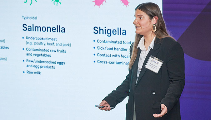 Female student presents in front of a video wall.