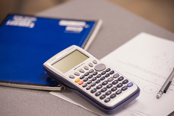 a calculator sits on top of a notebook next to a pencil