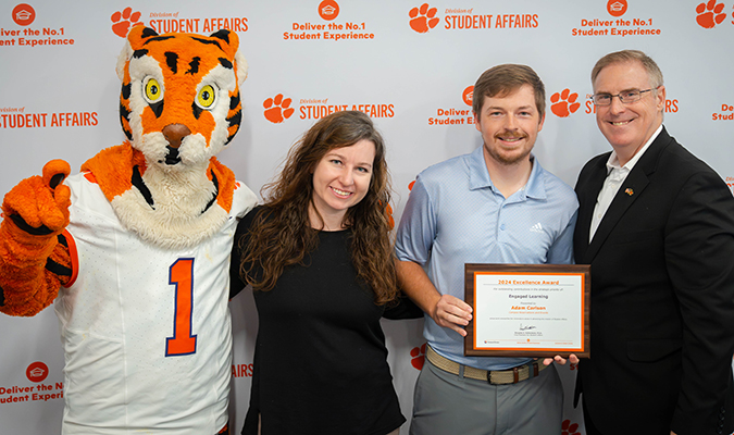 A Student Affairs staff member receives an individual excellence award from their presenter and Dr. Doug Hallenbeck, pictured with the Tiger mascot