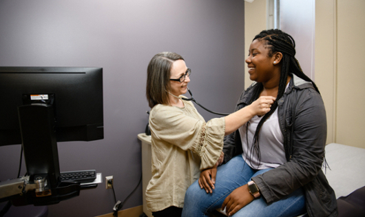 A medical provider listens to a patient's heartbeat 