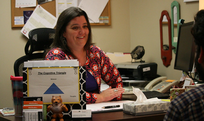 A mental health counselor talks with a male student in her office