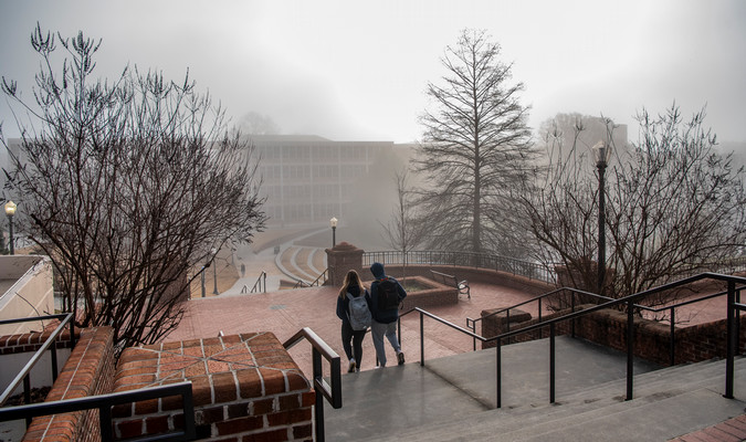 two students walking on campus on a winter day when there's not much sunlight