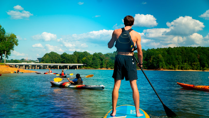person on a standup paddleboard with people kayaking in the background