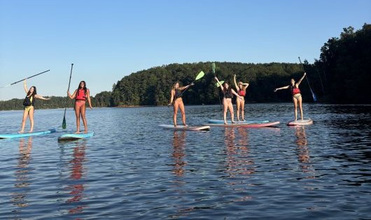 individuals on stand up paddleboards with paddles raised overhead in joy