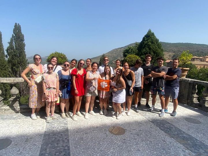 Group photo of 16 to 20 students holding orange Tiger rag