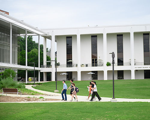 Students walking near a grassy area on campus.