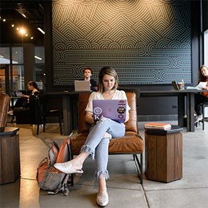 A student sits in a coffee shop working on their laptop