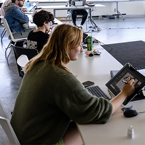 A student works on her tablet at a classroom table