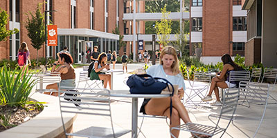 Students engage in outdoor study and relaxation in a campus courtyard.