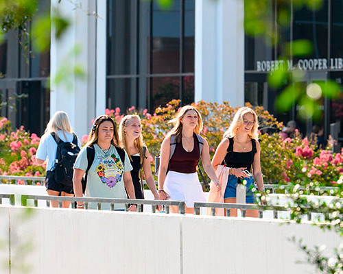 Students walk across the library bridge on Clemson's campus during summertime