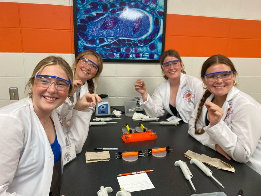 Students smiling around a lab table