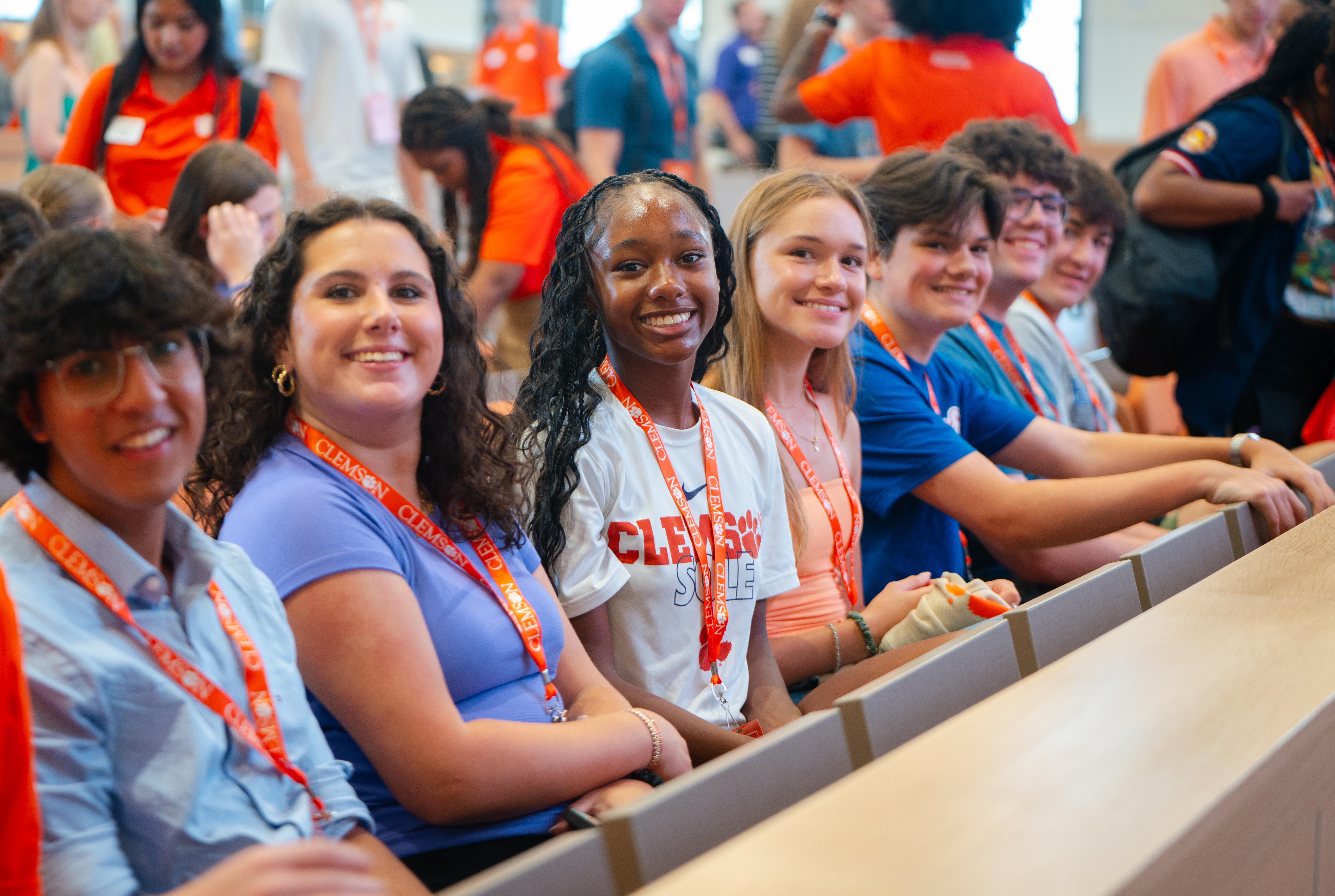 group of five male and female students sitting in a row smiling