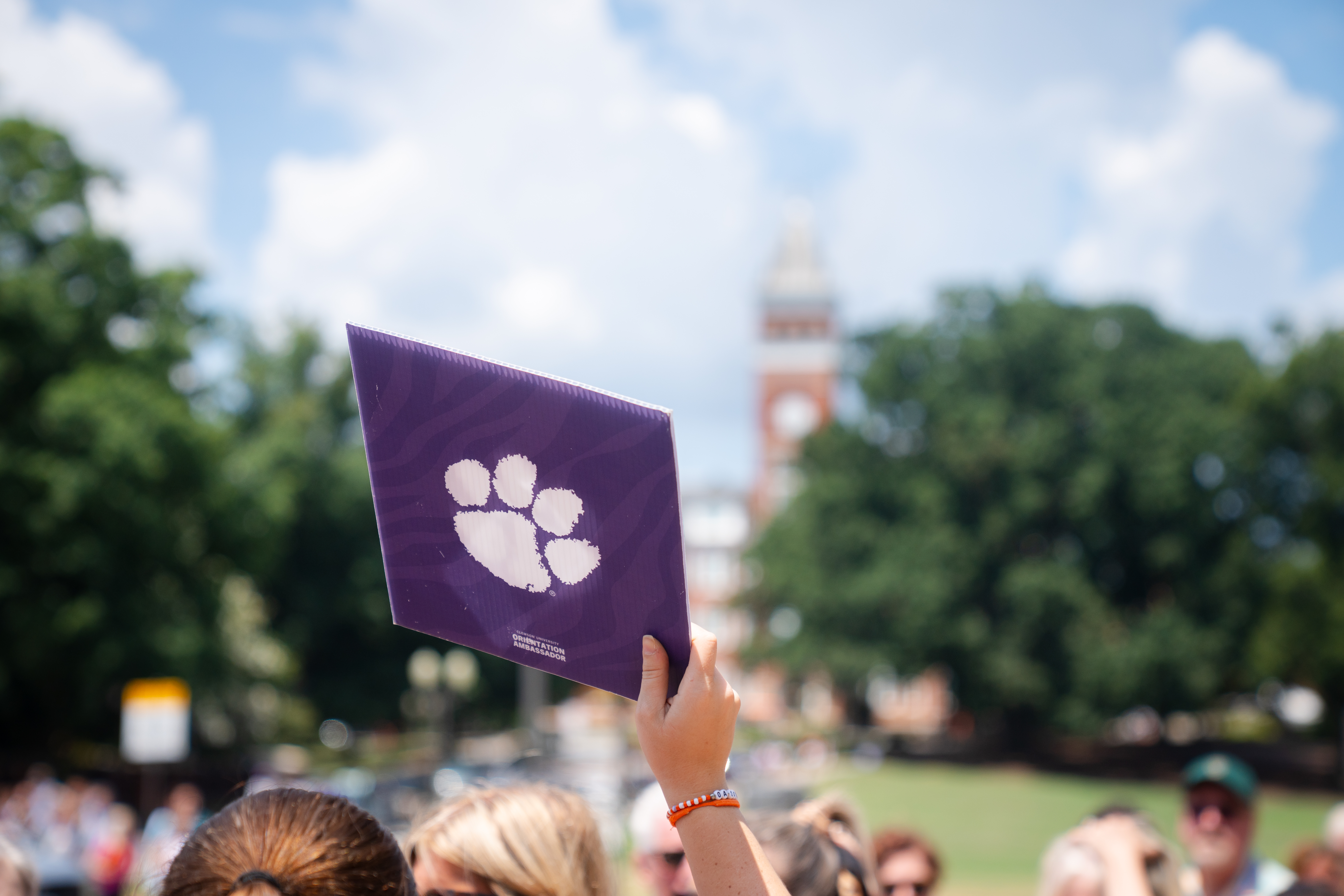 student holding purple sign with paw and Tillman Hall in back