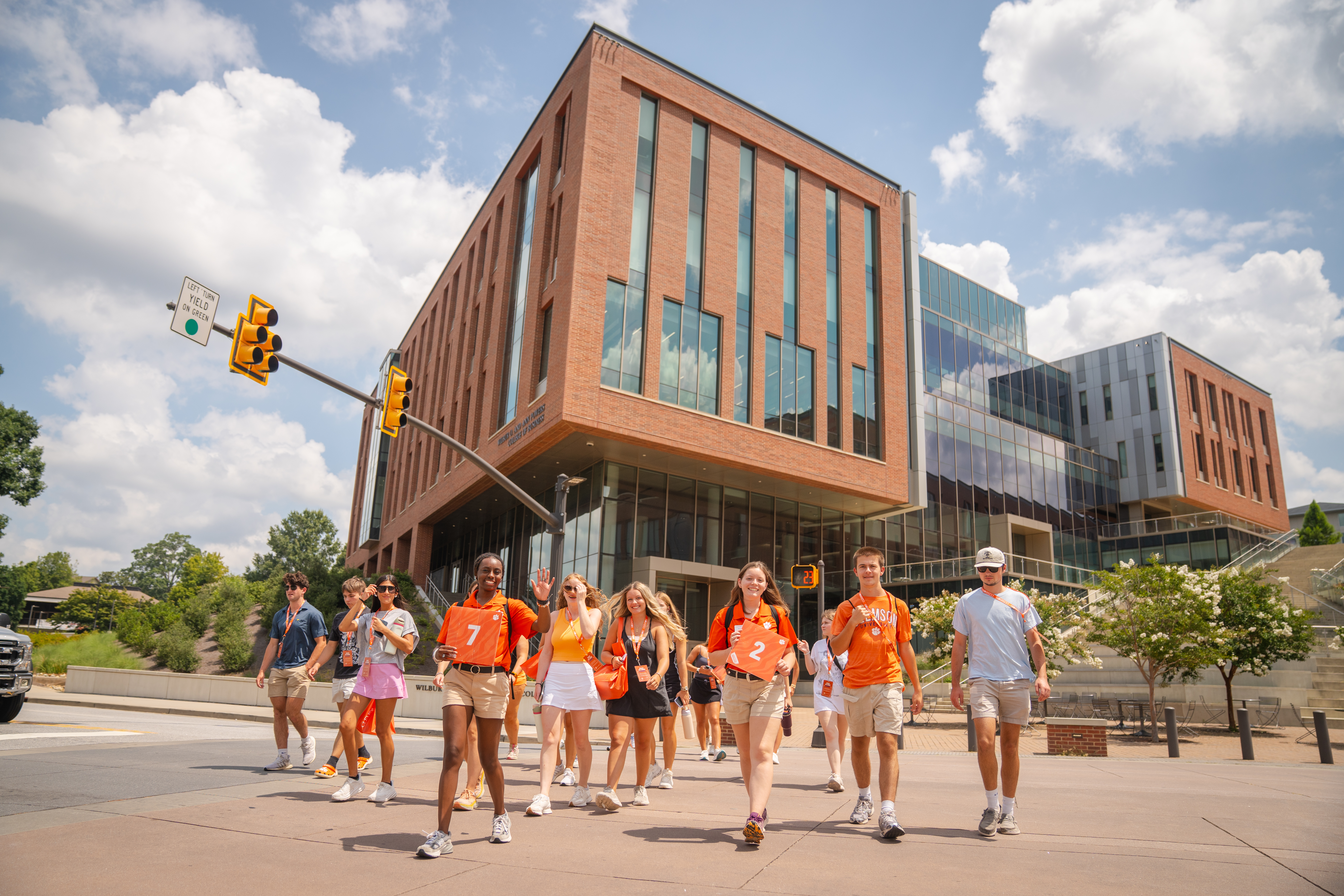 Two orientation ambassadors in orange polos guiding a group of students