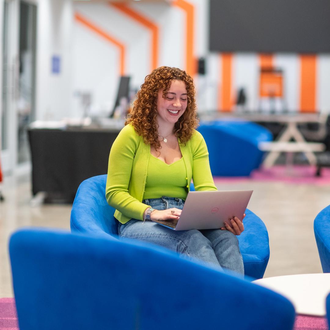 Female student in blue chair on laptop