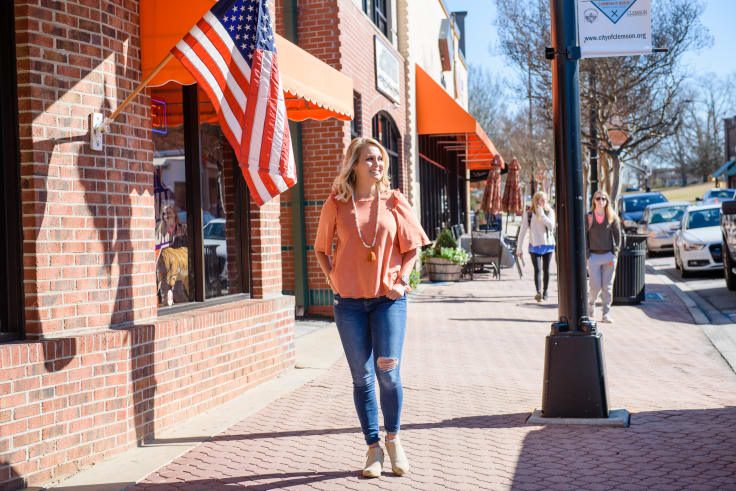 A female student walks along the street in downtown Clemson