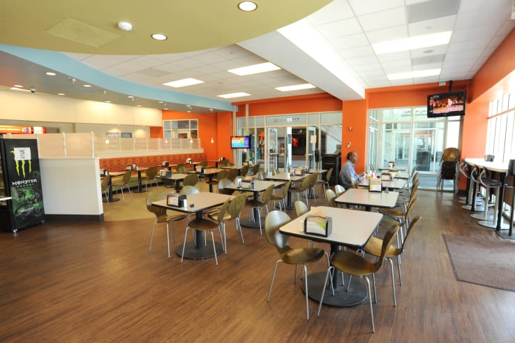Groups of chairs and tables with televisions hanging overhead in eastside food court.