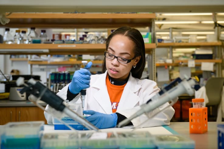 A student conducts research in a laboratory with a pipet