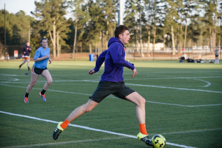 A male student plays soccer on the snow center intramural field