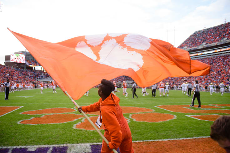 A student waves a flag emblazoned with a Clemson Paw in the end zone of memorial stadium. 