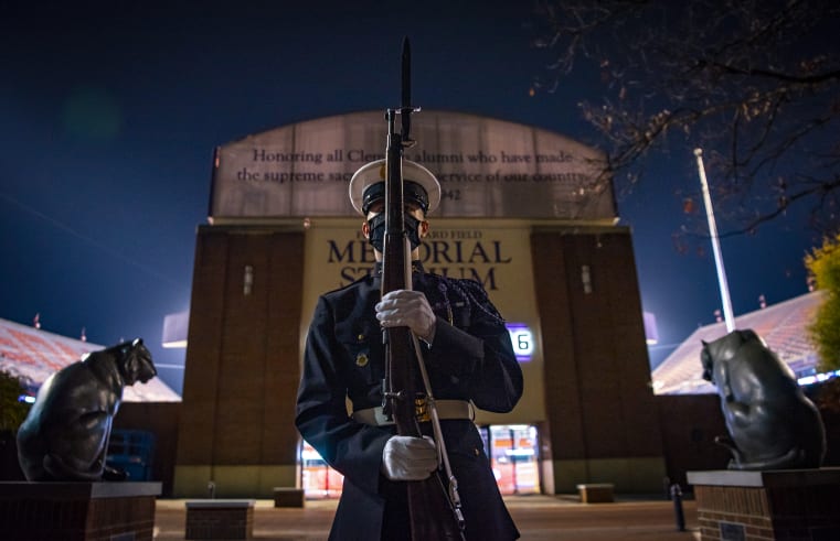 A solider in full dress stands in front of memorial stadium at the scroll of honor 