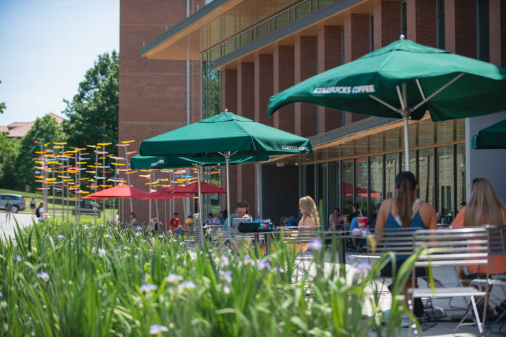 Tables with Umbrellas line the sidewalk outside of the Core Campus Starbucks