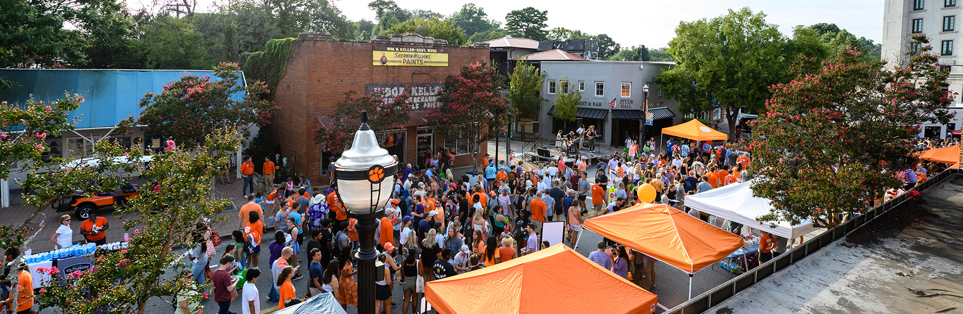 Street filled with purple and orange canopies with a large crowd of people during the welcome back festival.